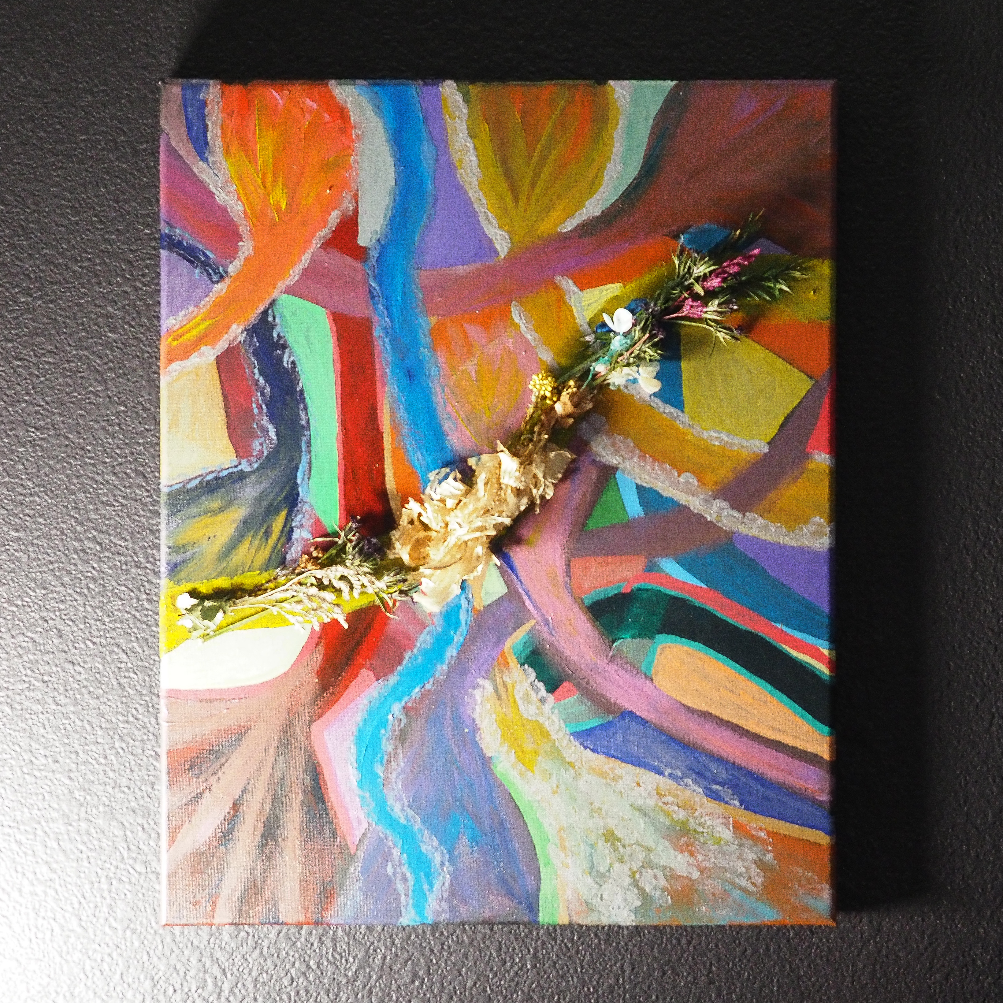 Abstract painting of overlapping colorful shapes with dried florals and bold lines