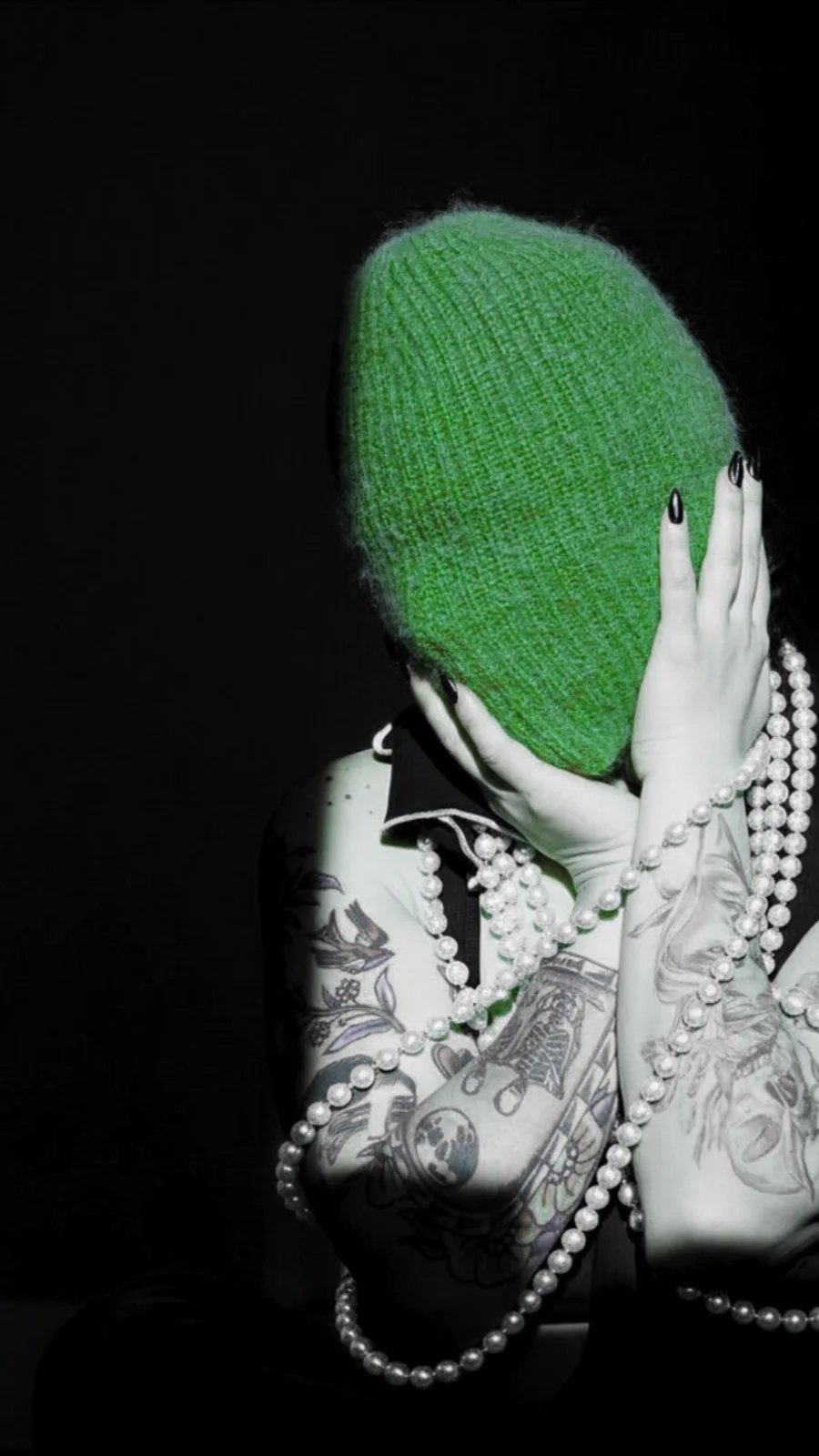 Conceptual portrait with a green veil and strands of pearls